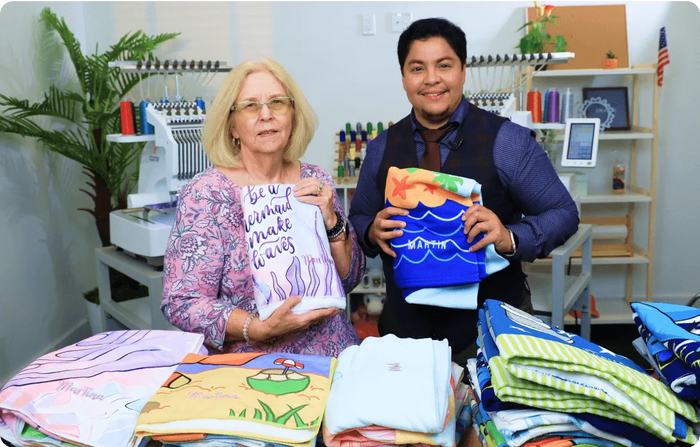 Two people holding printed fabric samples in a workshop setting